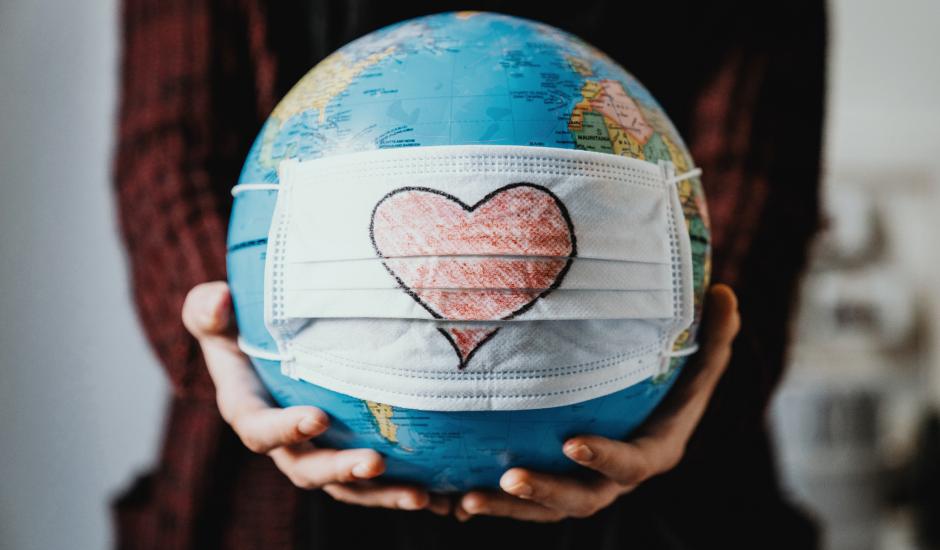 hand holding the globe with a medical mask on which a heart is drawn